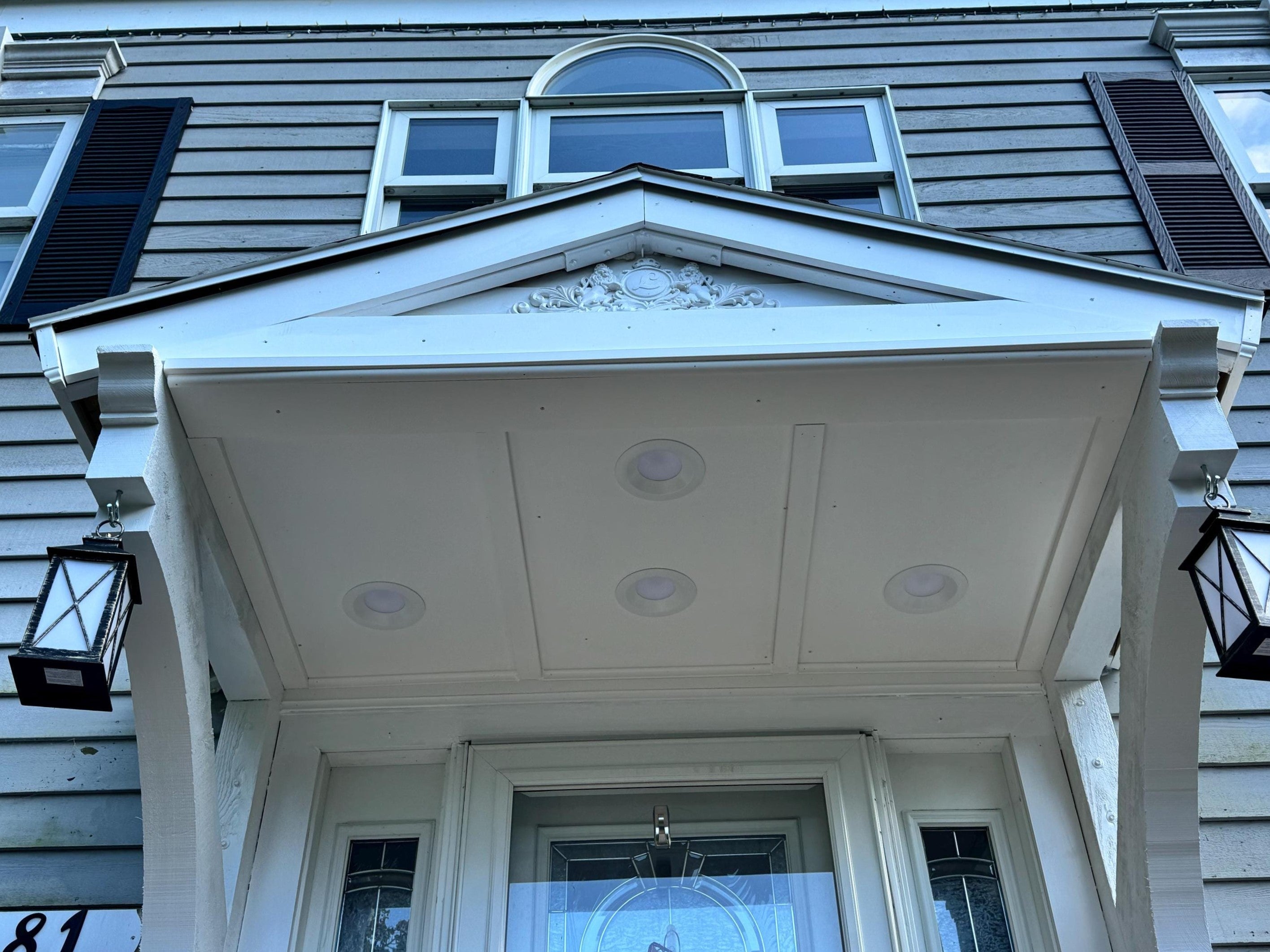 A beautifully renovated entrance features a classic architectural design with decorative elements. The entryway is illuminated by stylish lanterns, enhancing its charm.