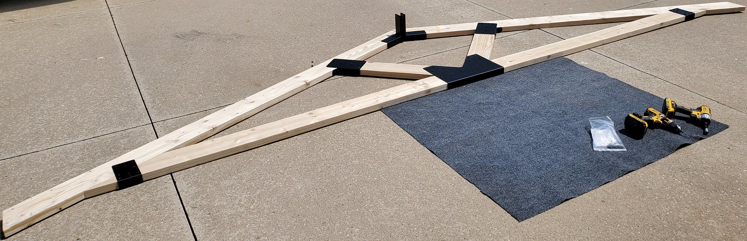 Various wooden pieces are arranged on a floor, ready for assembly. Tools are placed nearby, indicating an ongoing construction project.