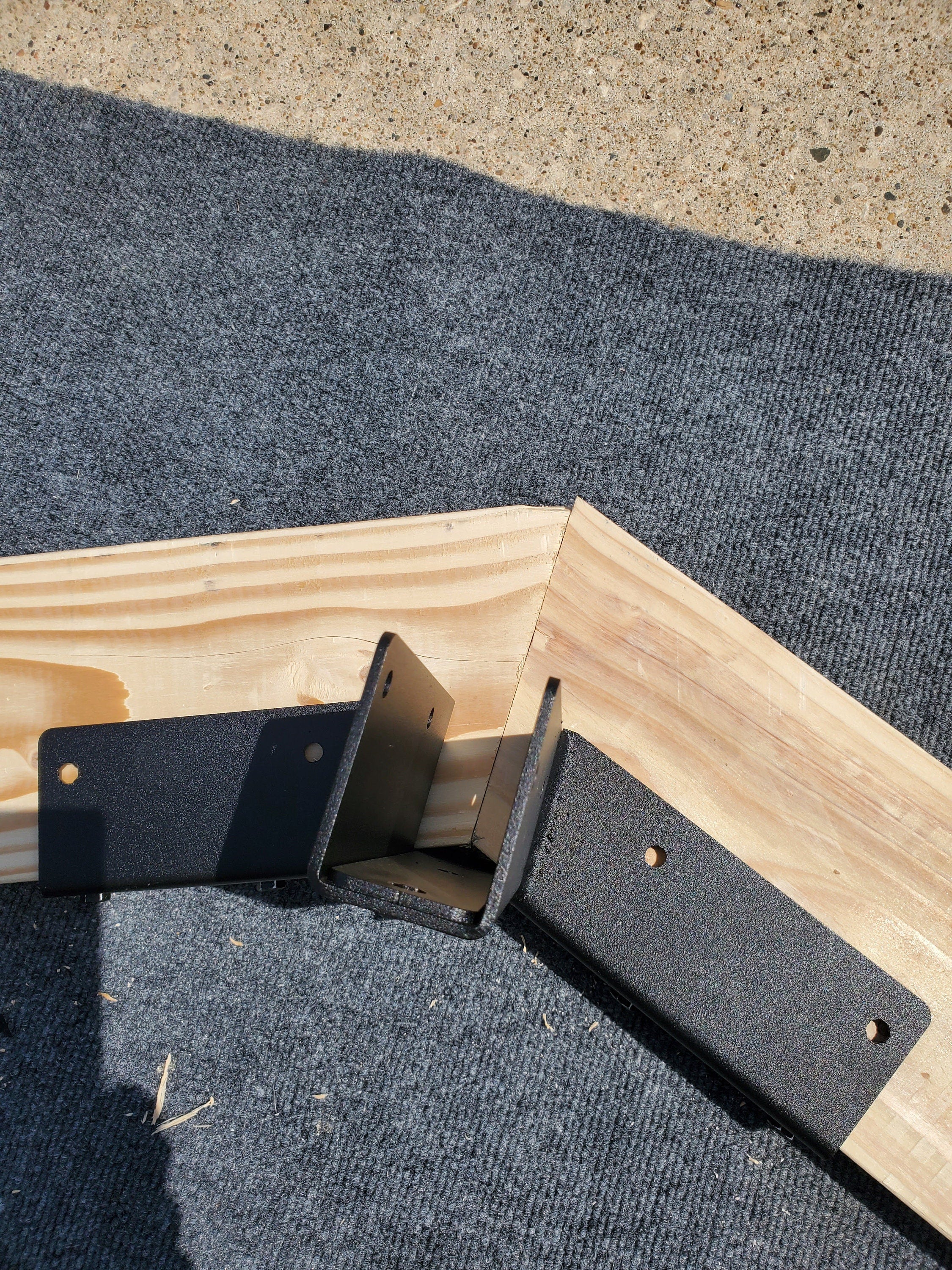 A close-up view of sturdy metal brackets securing wooden beams together, providing essential support for a roof structure during assembly.