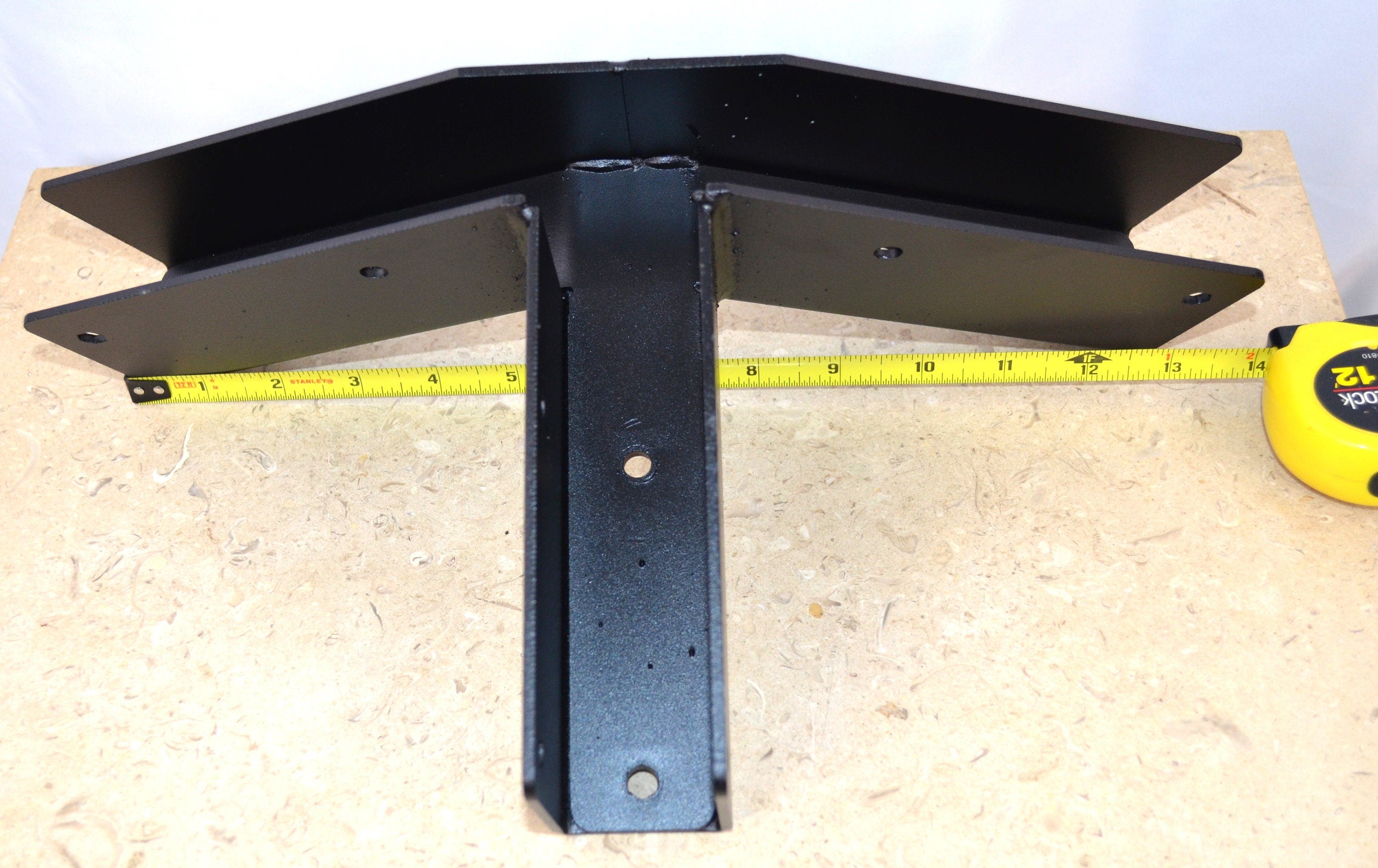 a black truss peak rafter bracket with a tape measure showing its size