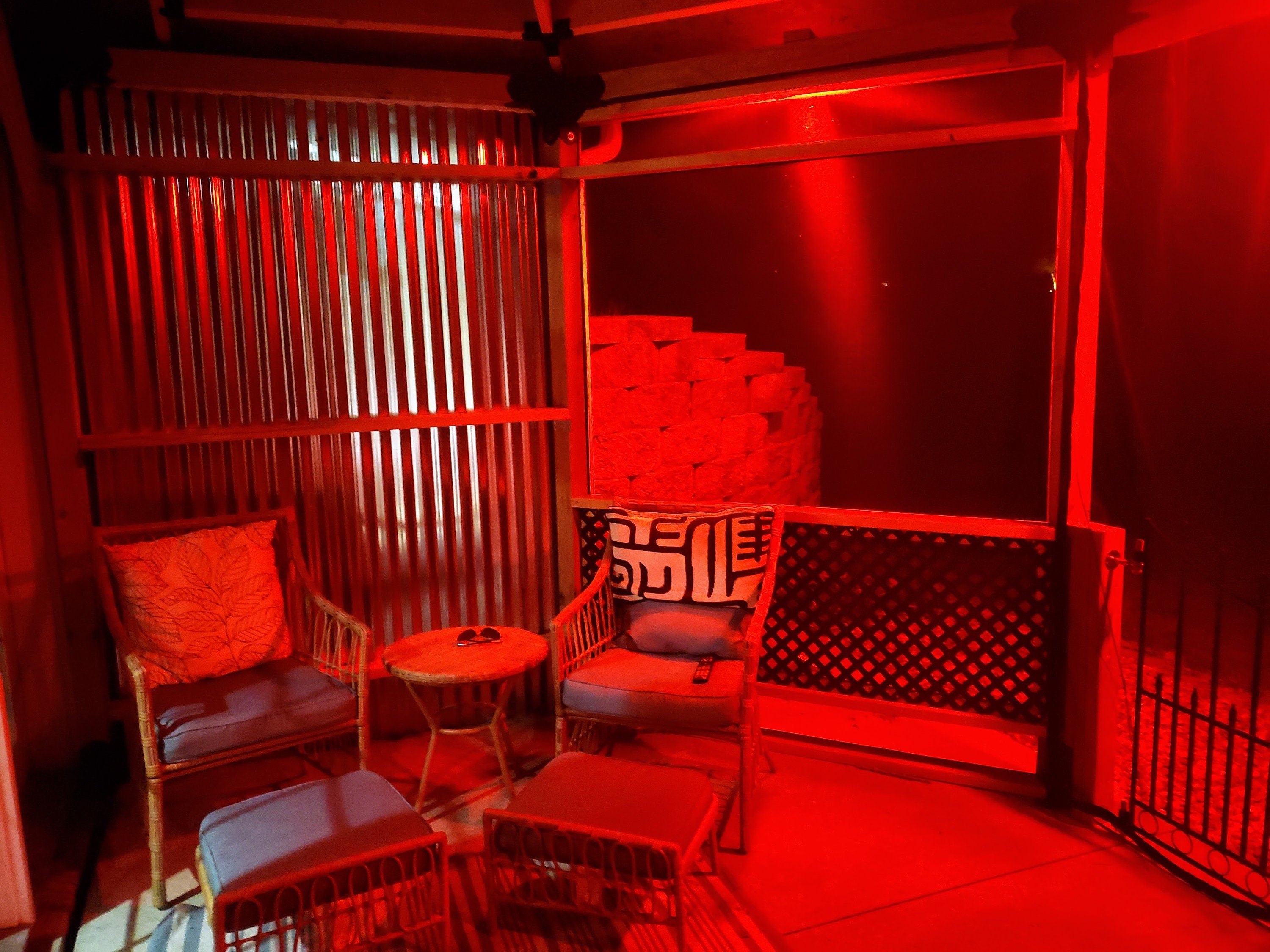 A room with chairs and a table, bathed in a vibrant red light, creating a dramatic atmosphere.