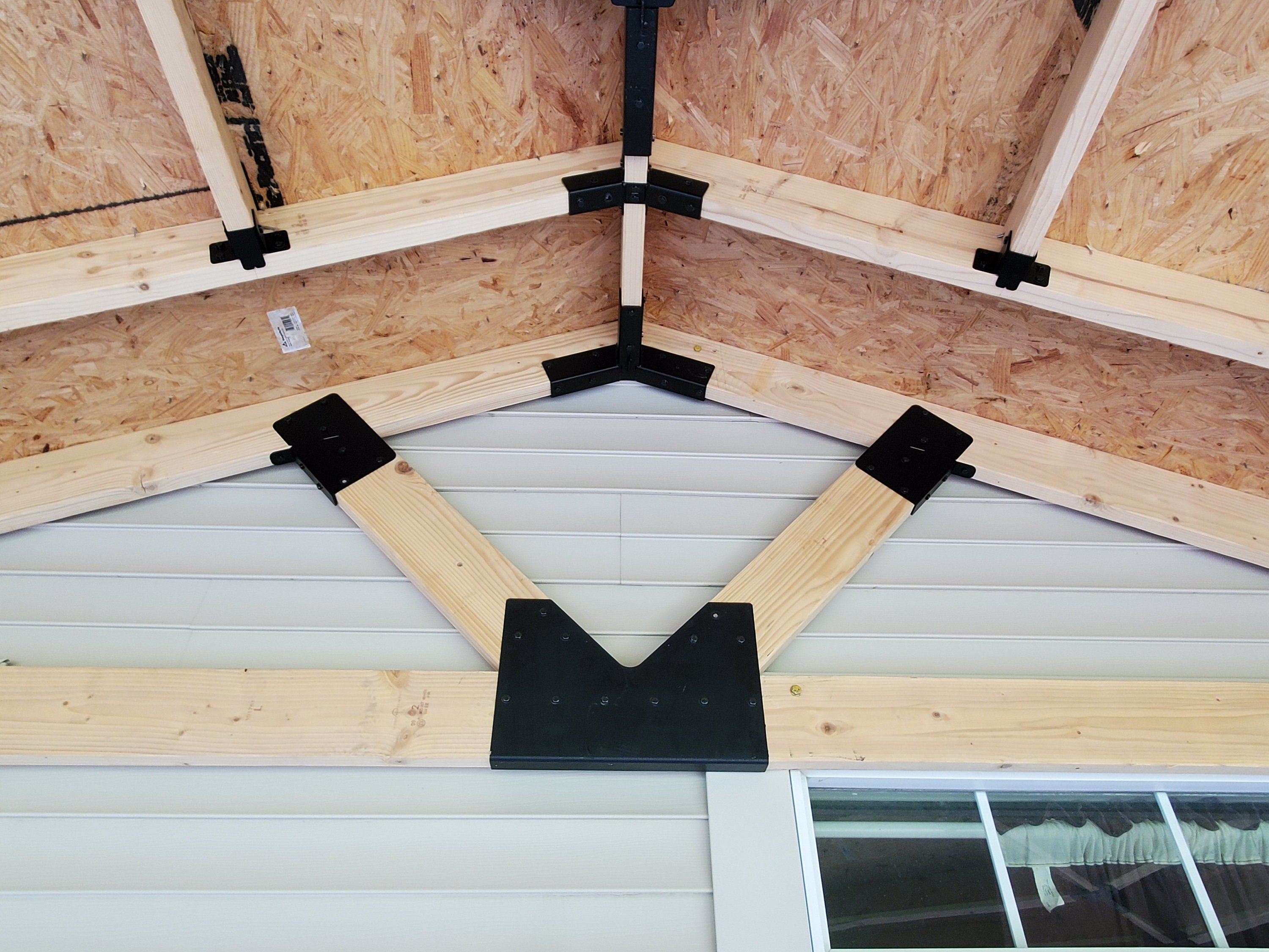 roof under construction showing intricate metal brackets used for securing lumber joints