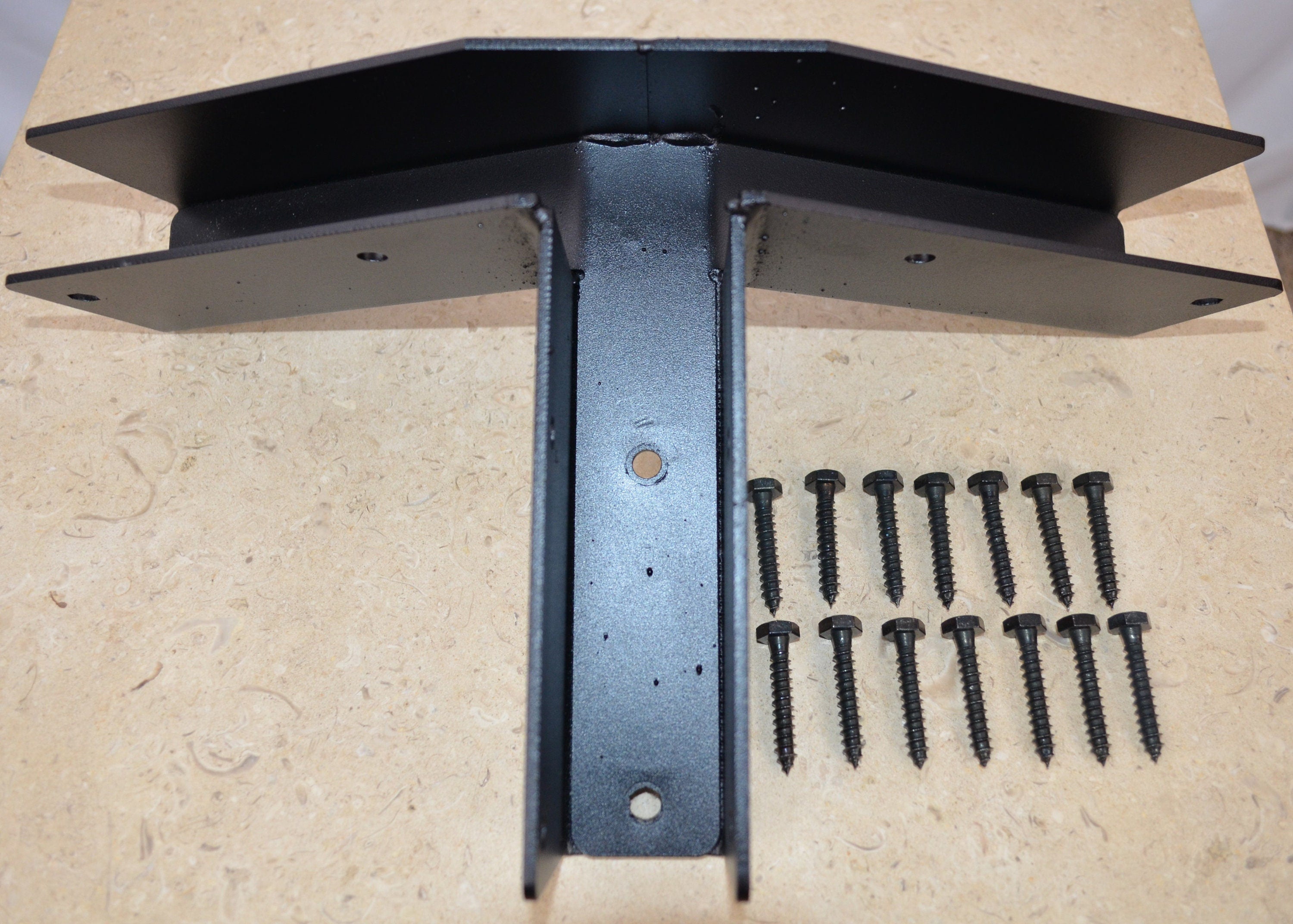 A partial hexagon open end ridge rafter bracket, accompanied by lag screws, is presented on a white surface, ideal for roofing support and installation.