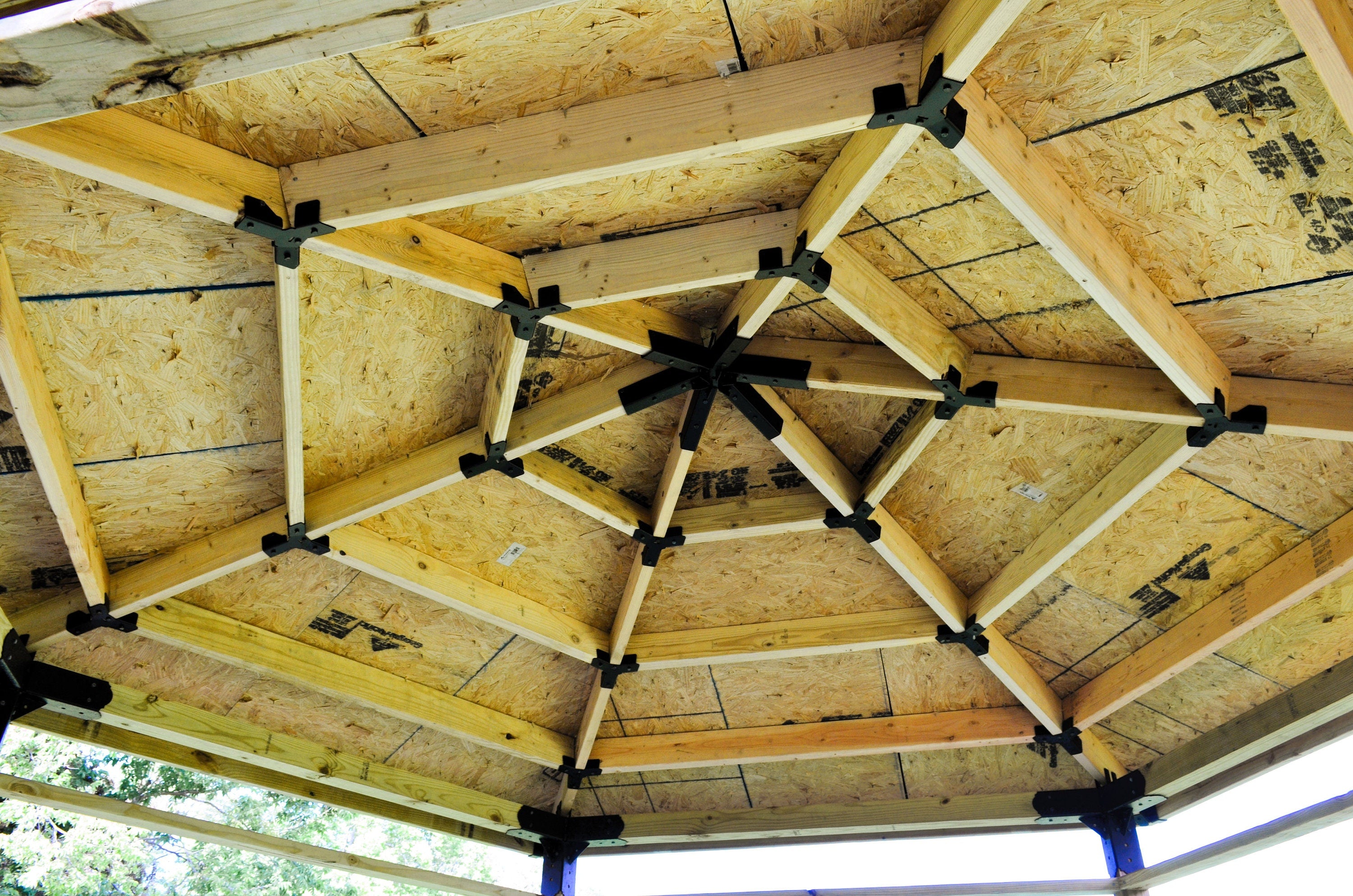 Close up view of the inner framing of a hexagon roof structure showing the hexagon spider, crosstie brackets, rafters and crosstie beams