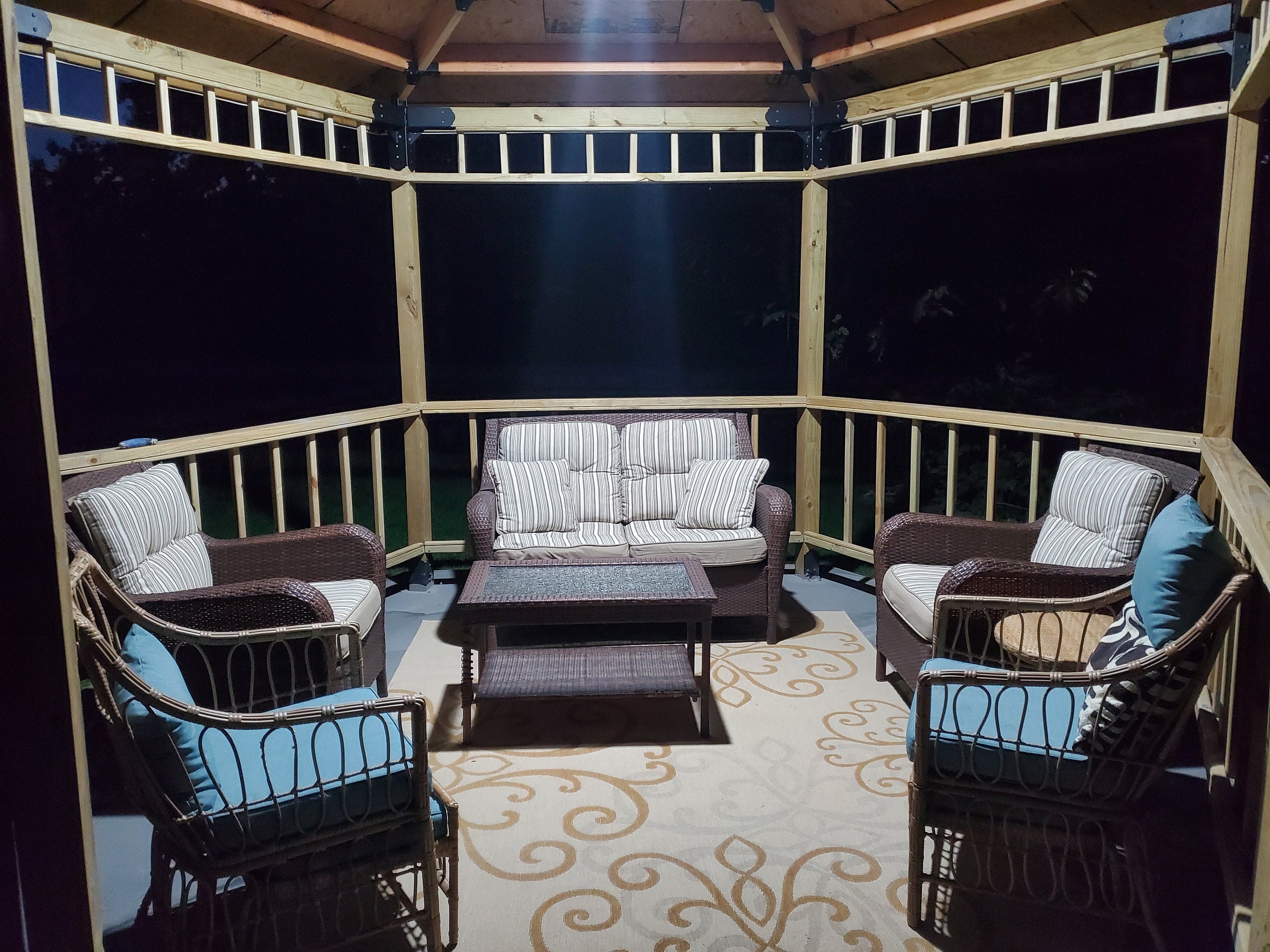 This inviting outdoor lounge area showcases a wooden structure with comfortable seating, and a table  perfect for summer entertainment and relaxation.