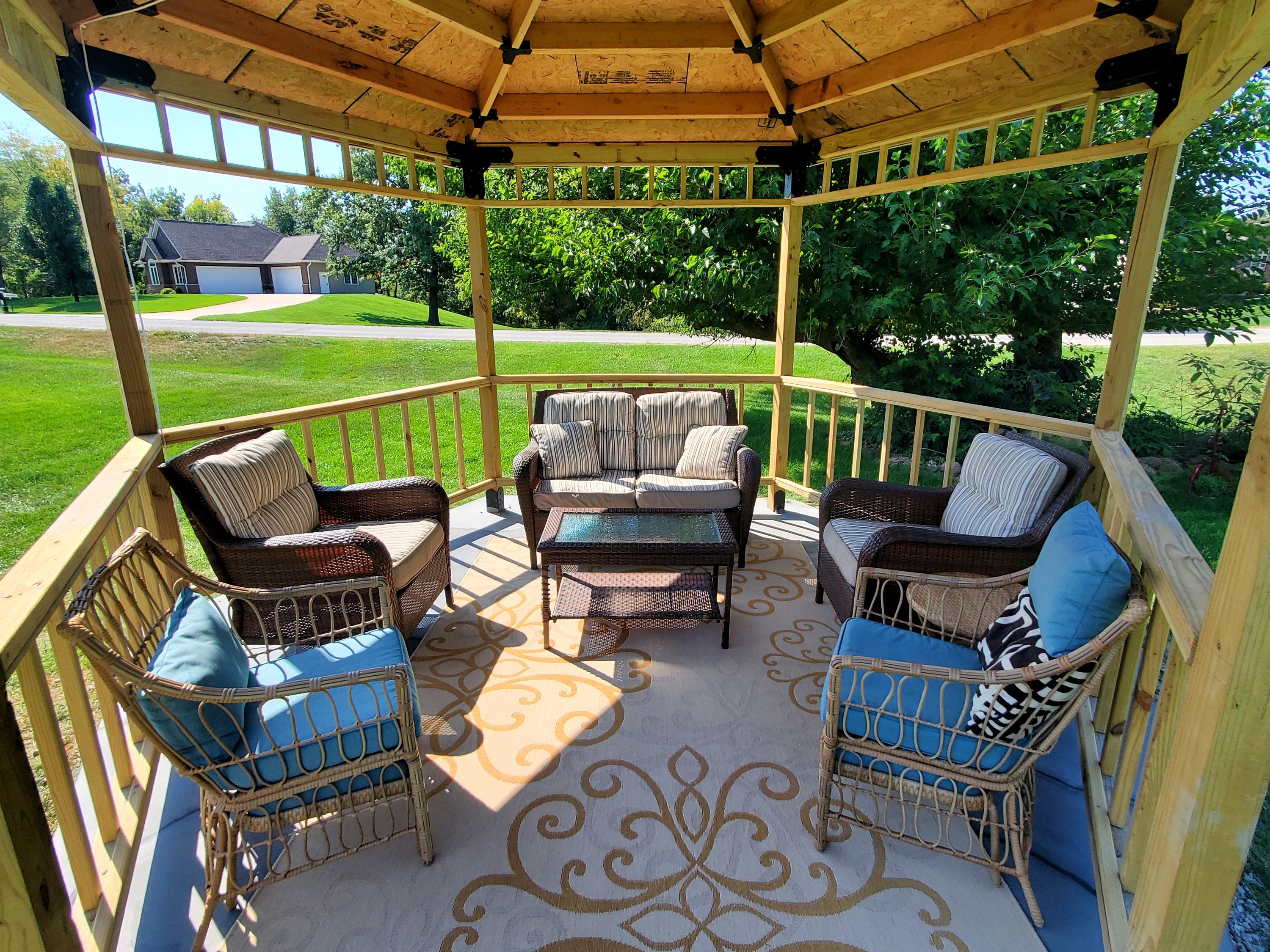 This inviting outdoor lounge area showcases a wooden structure with comfortable seating and a table, perfect for summer entertainment and relaxation.