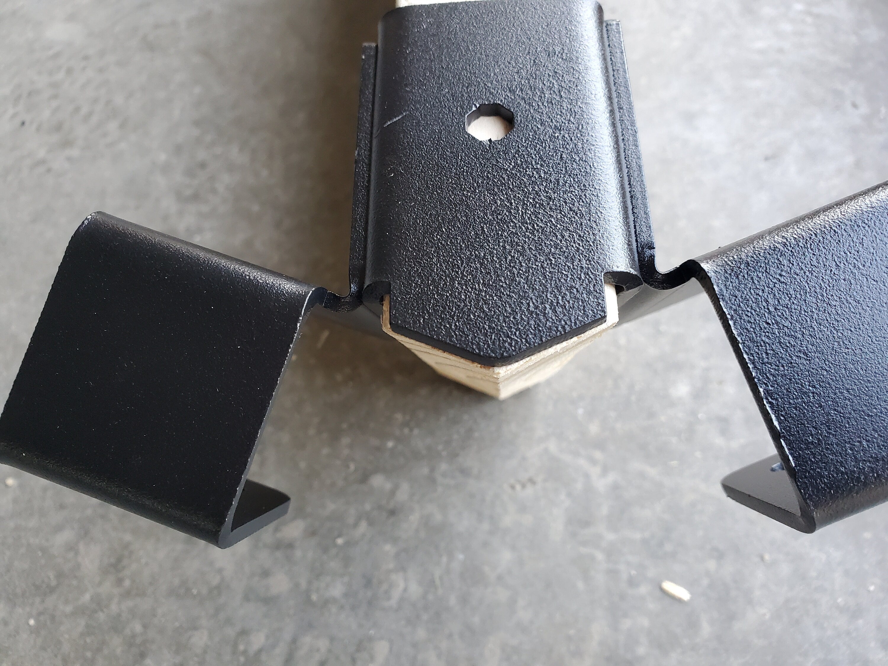 a metallic bracket is securely fastened to a wooden beam, providing sturdy support in a construction workshop environment, demonstrating functional design.