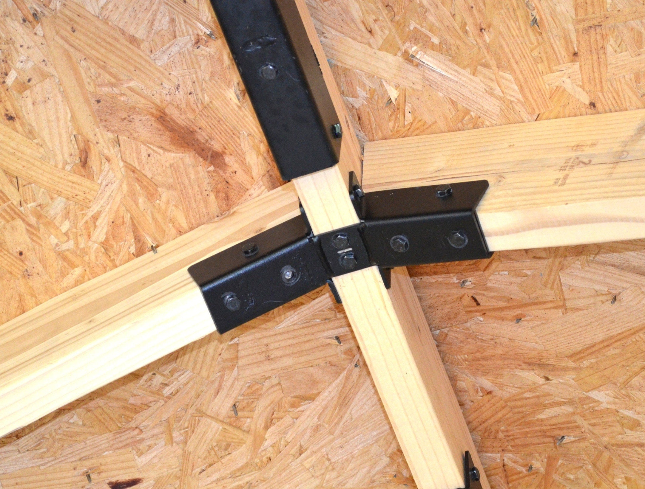 Close up view of a 5-12 Ridge Rafter bracket as installed on a roof with a ridge beam and two rafters