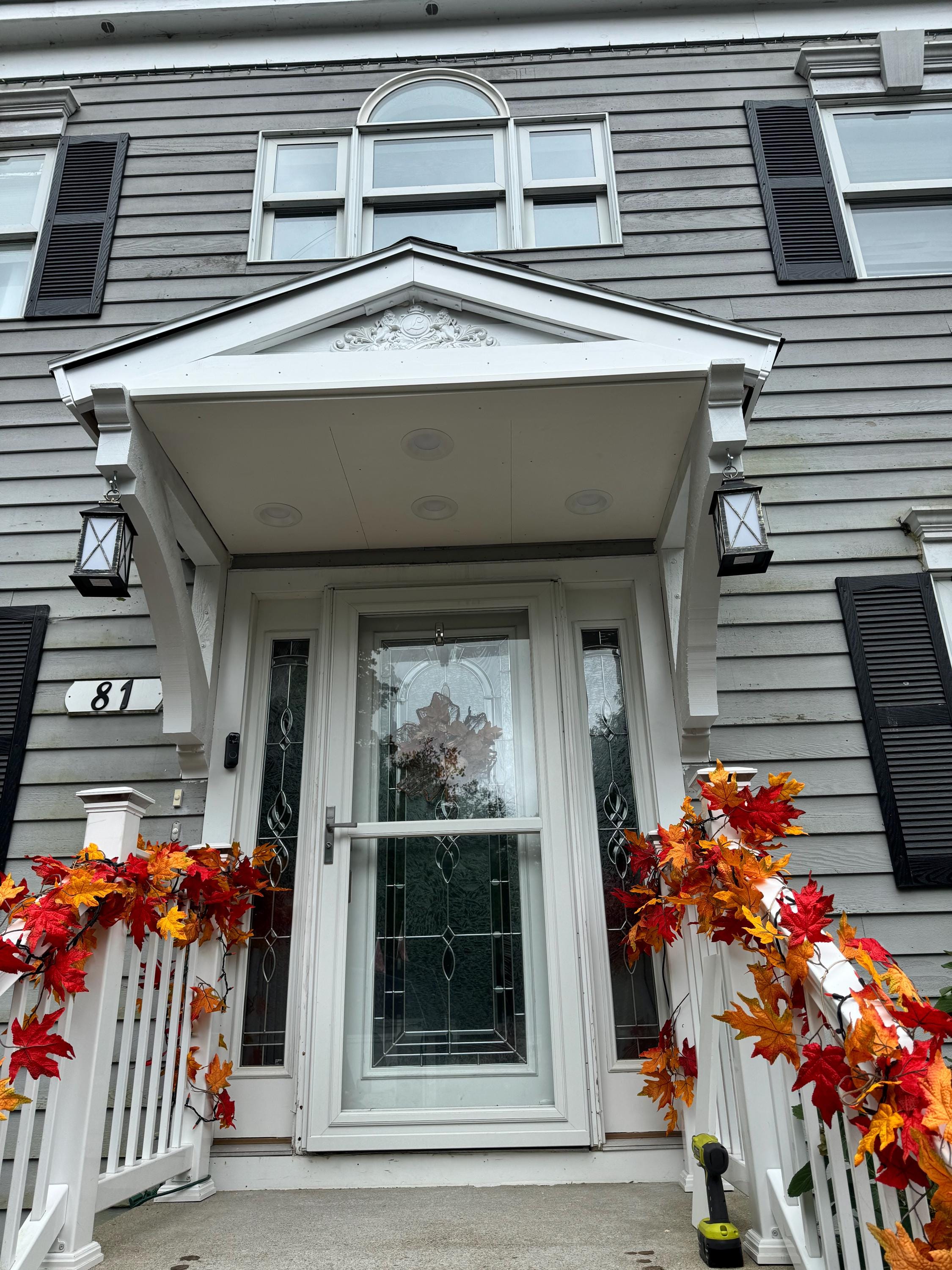 The entrance of the house is adorned with vibrant autumn leaves and glowing lanterns, creating a warm ambiance in the quiet night. It invites all who pass by.